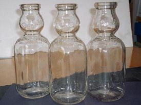 Three empty milk bottles are sitting on a table