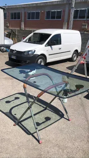 Primo piano delle sospensioni anteriori metalliche, delle ruote e dei componenti della trasmissione di un'auto su uno sfondo bianco pulito.