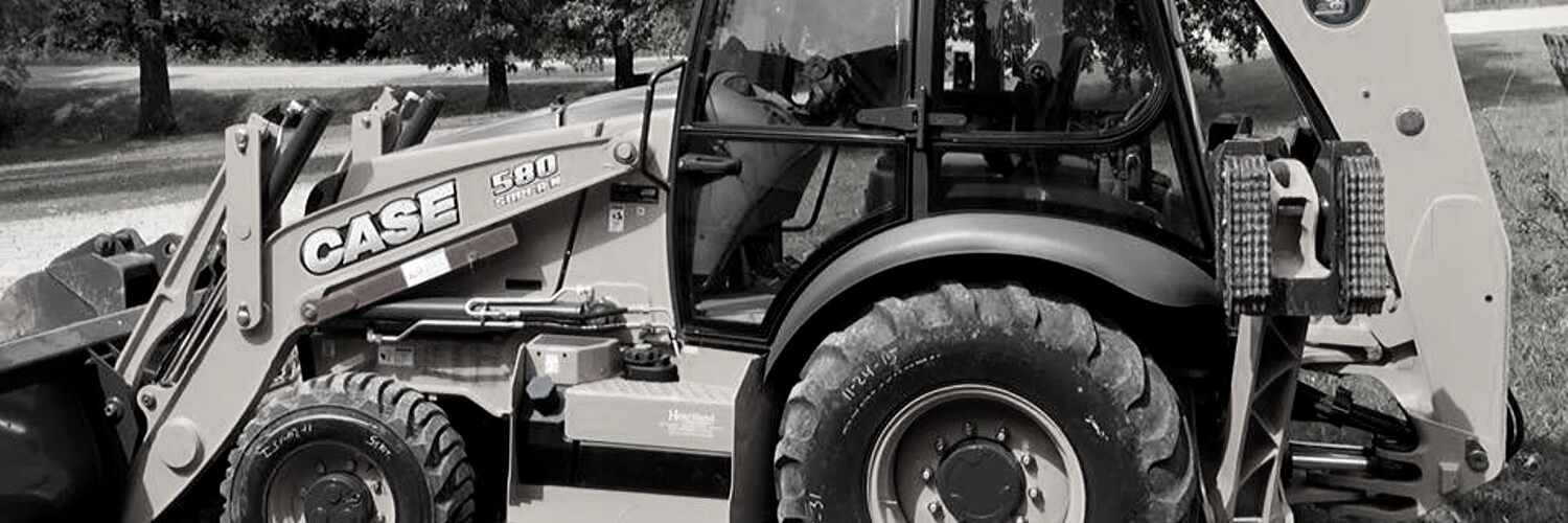 A Case backhoe loader parked outdoors in an open field, shown from the side.