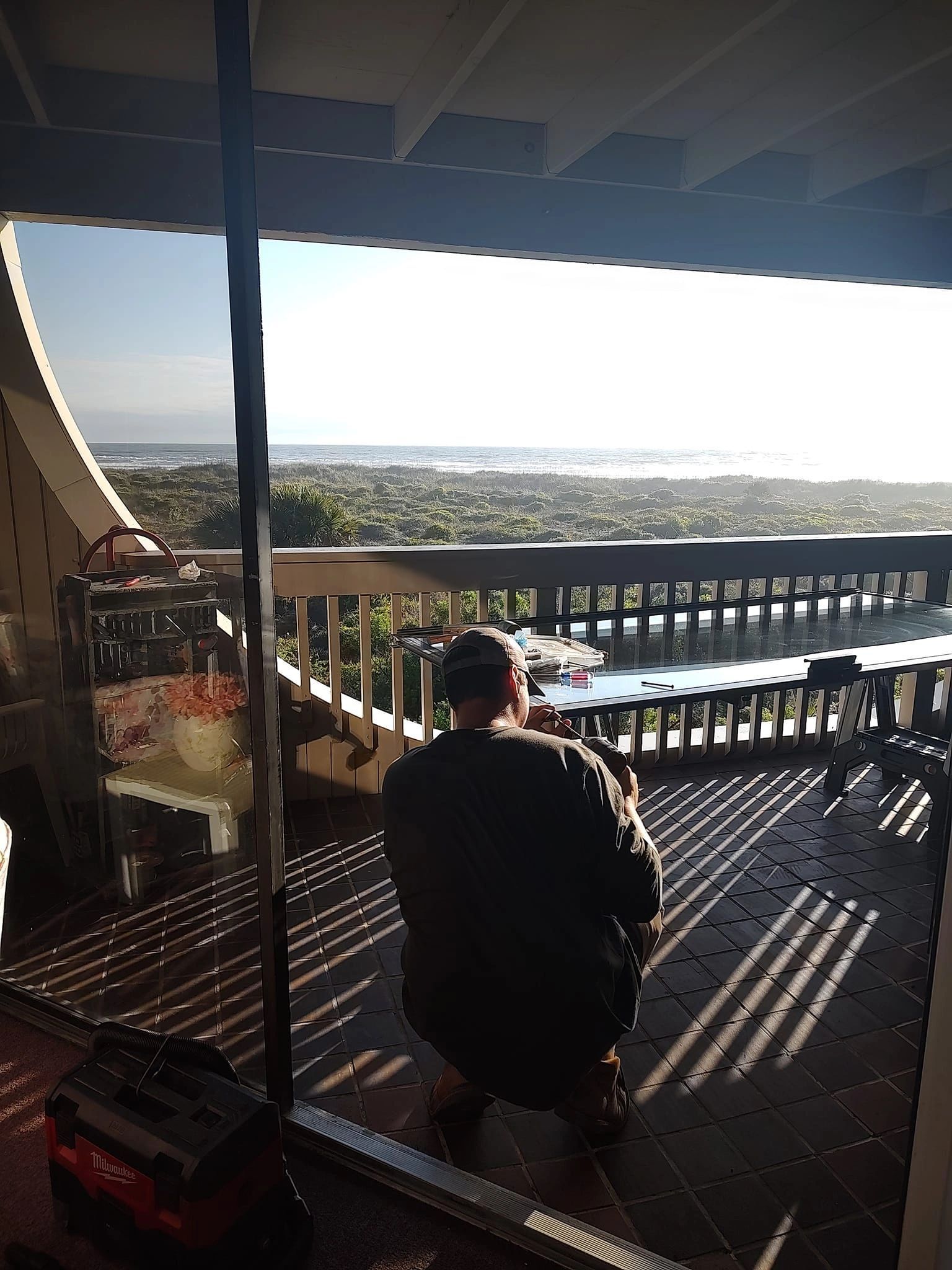 A man is sitting on a balcony overlooking the ocean.