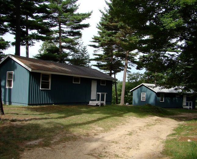 Two blue houses are sitting next to each other on a dirt road – Oxford, MI - Camp Oakland