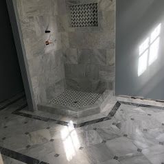 A bathroom with a walk in shower and a marble floor. Bathroom Remodeling New Orleans