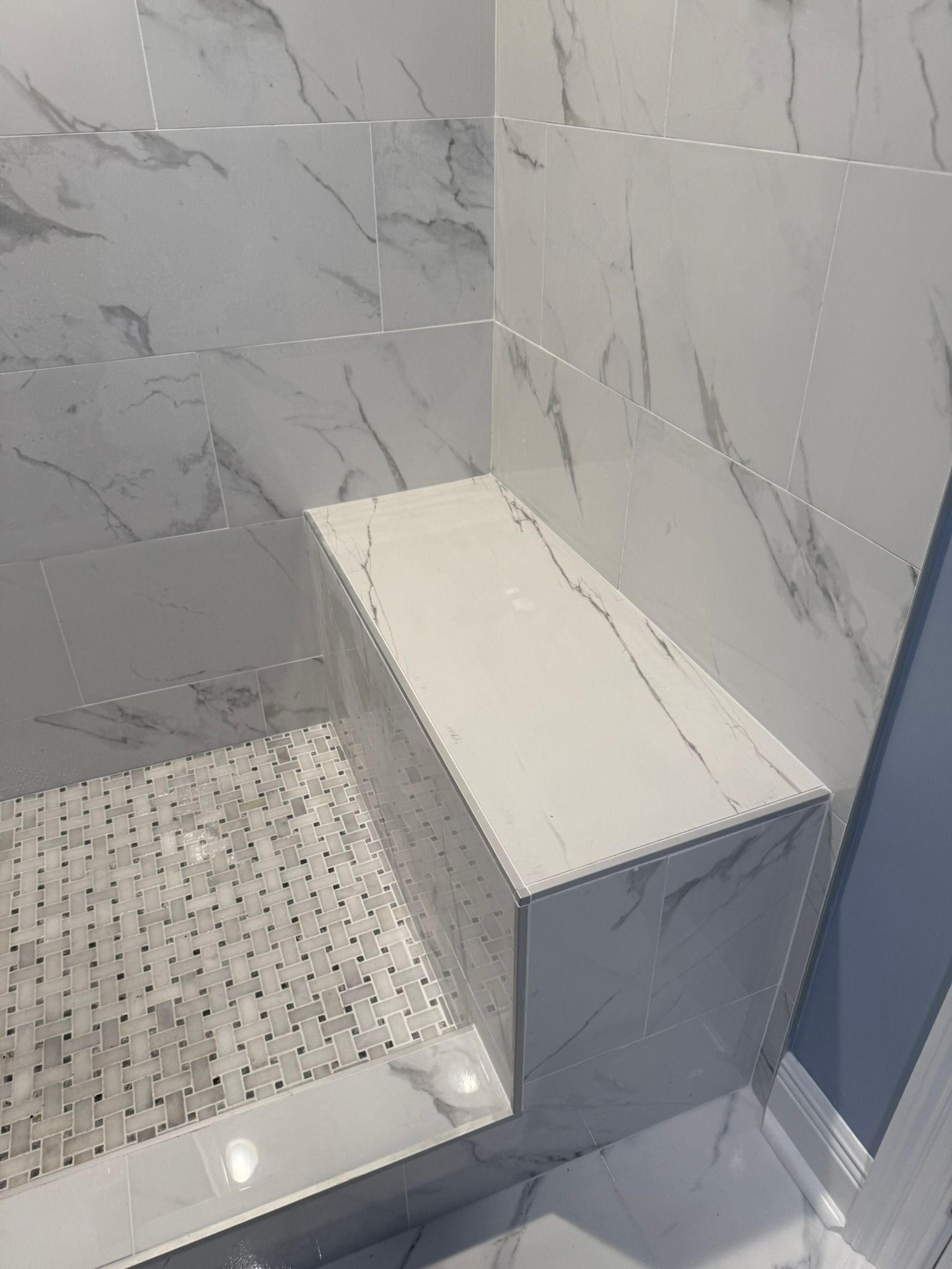 A bathroom with marble tiles and a walk in shower Luxury Bathroom Remodel New Orleans 