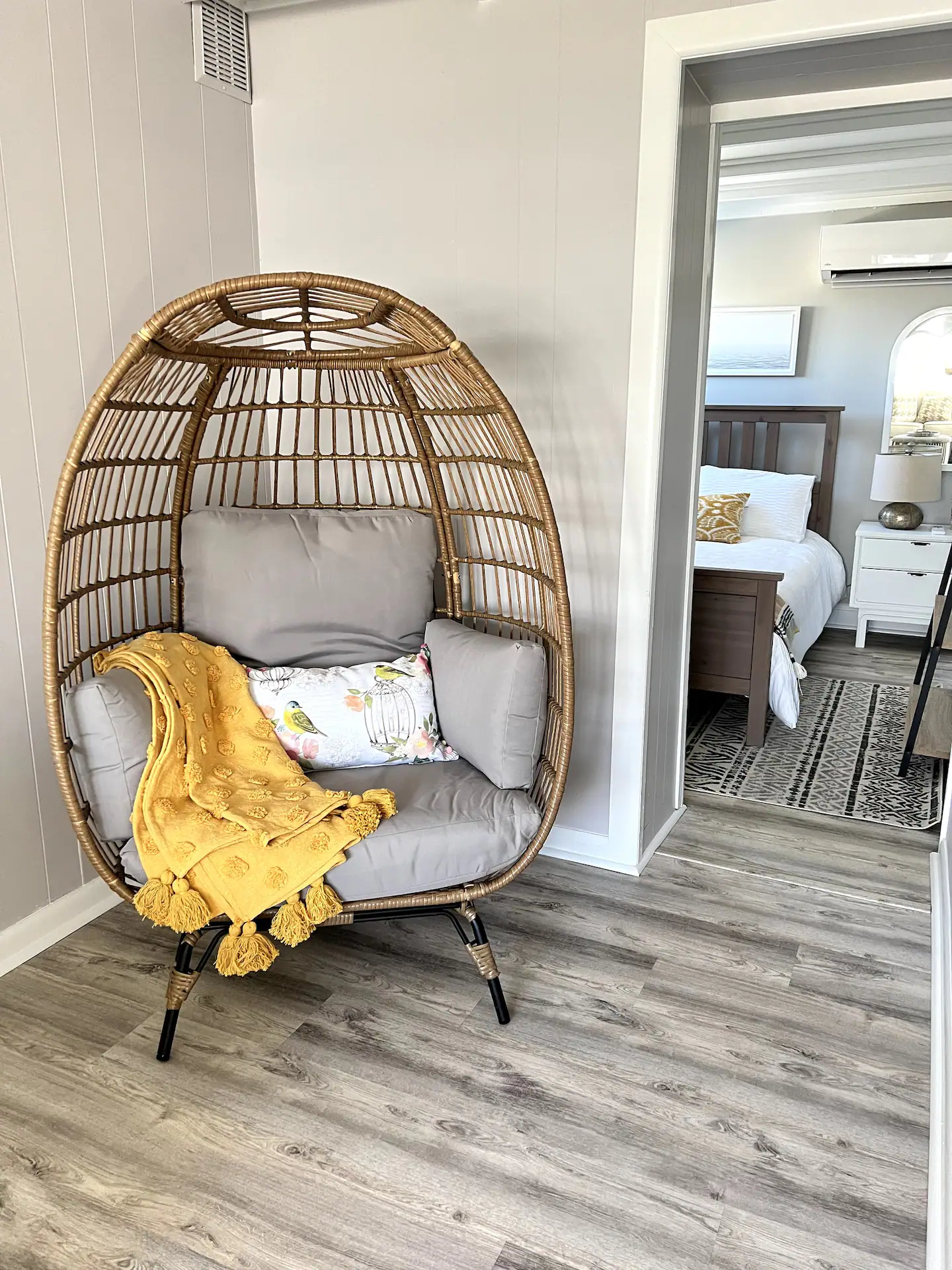 A wicker chair with a yellow blanket on it is sitting in a room next to a bed.