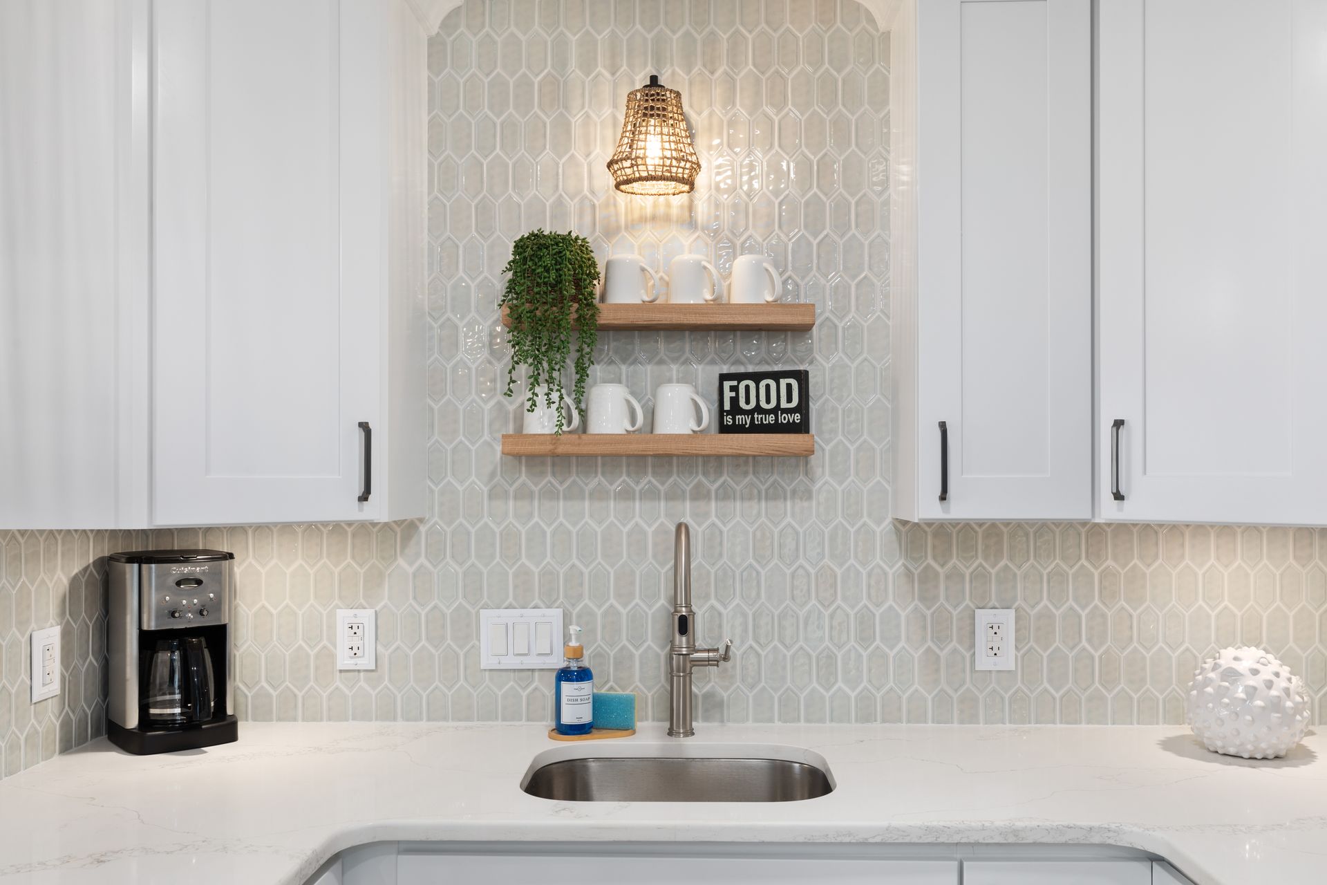 A kitchen with white cabinets , a sink , and a coffee maker.