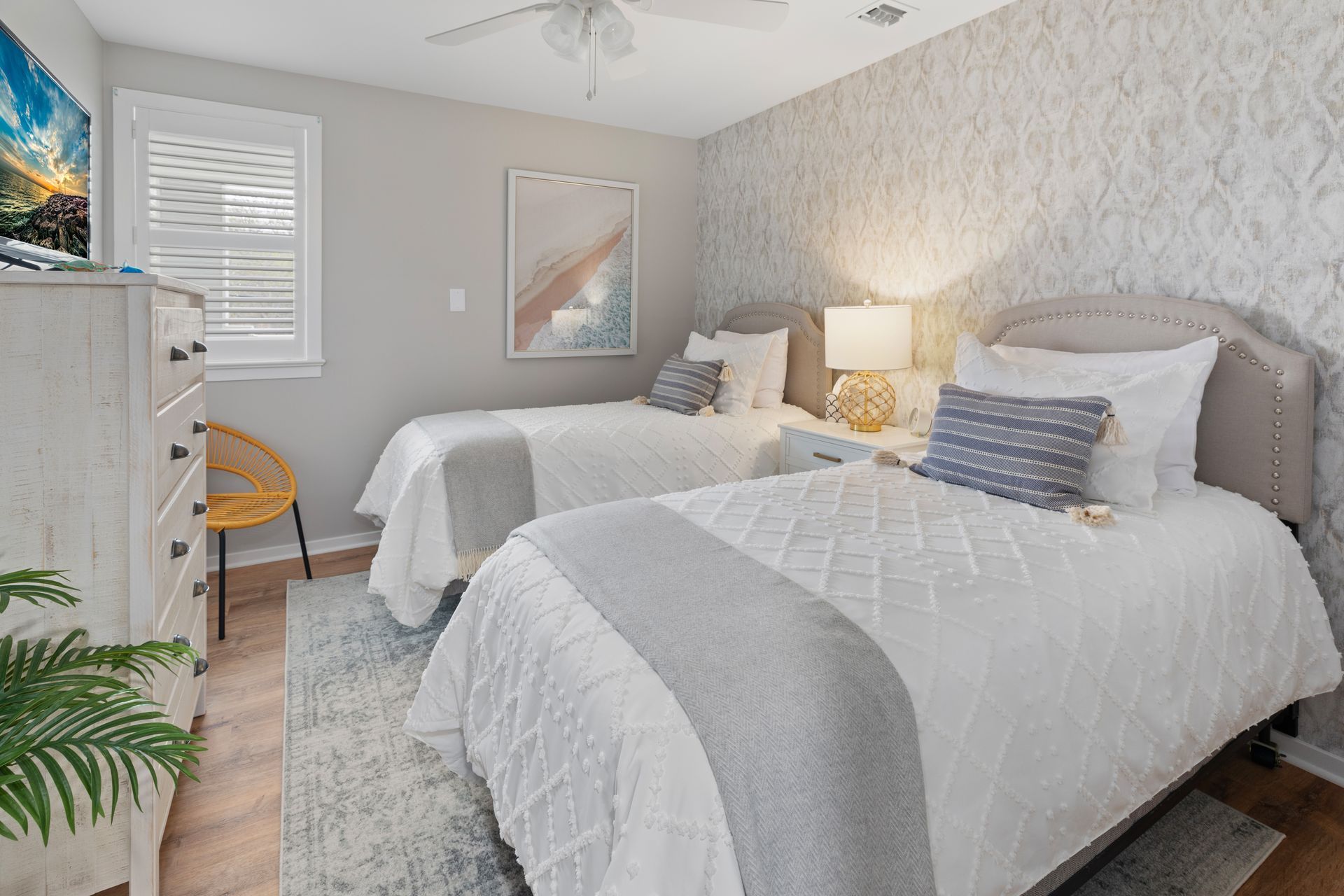A bedroom with two twin beds , a dresser , and a television.
