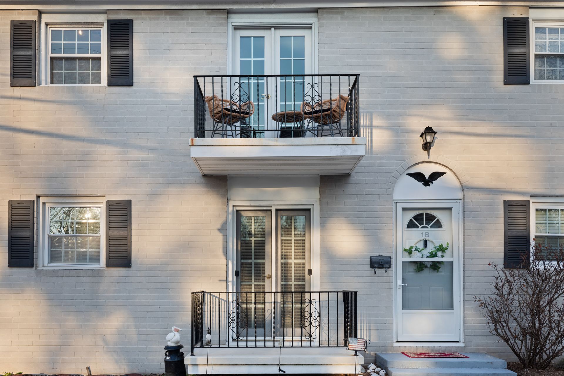 A white house with black shutters and a balcony
