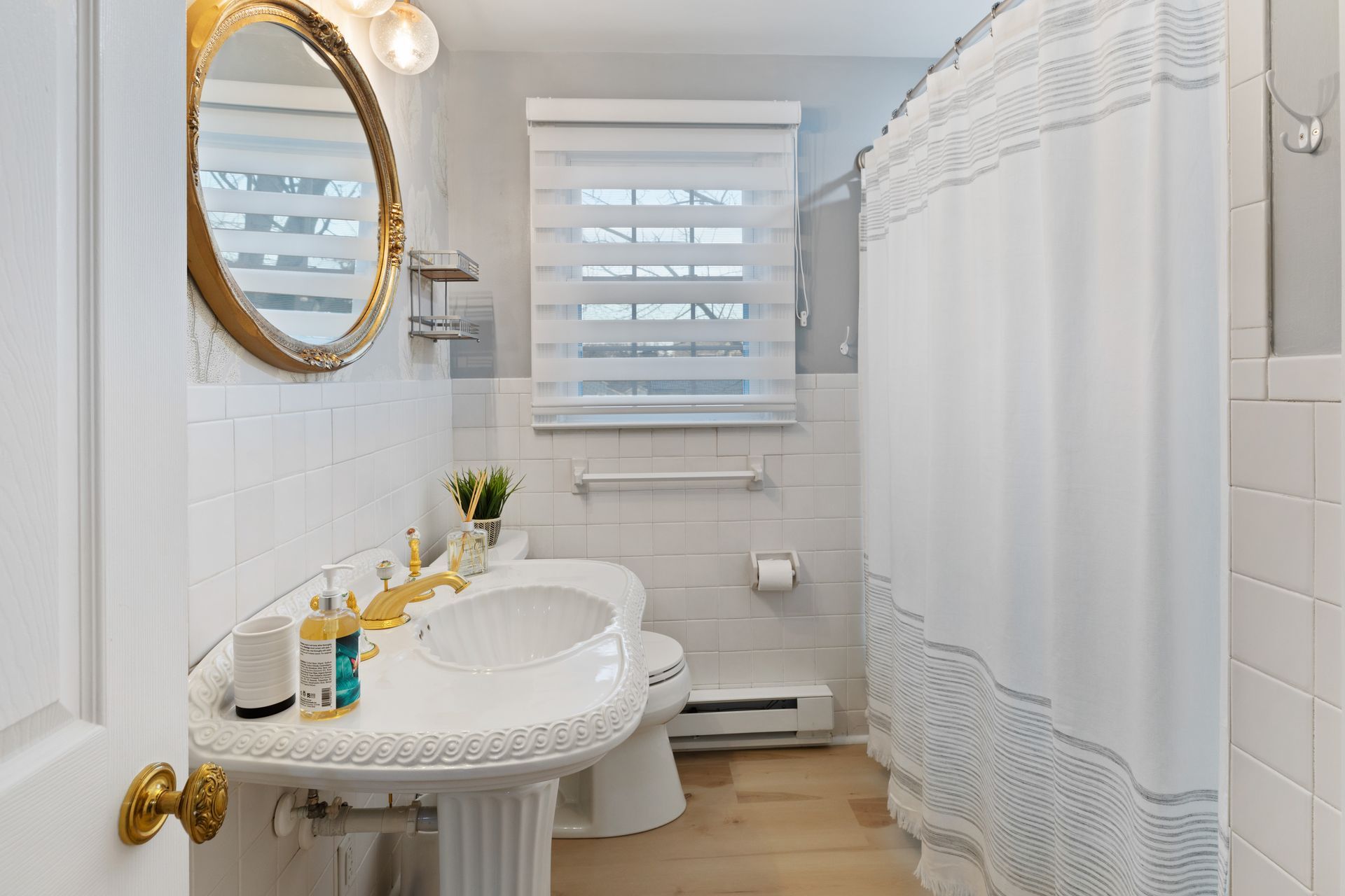 A bathroom with a sink , toilet , shower curtain and mirror.