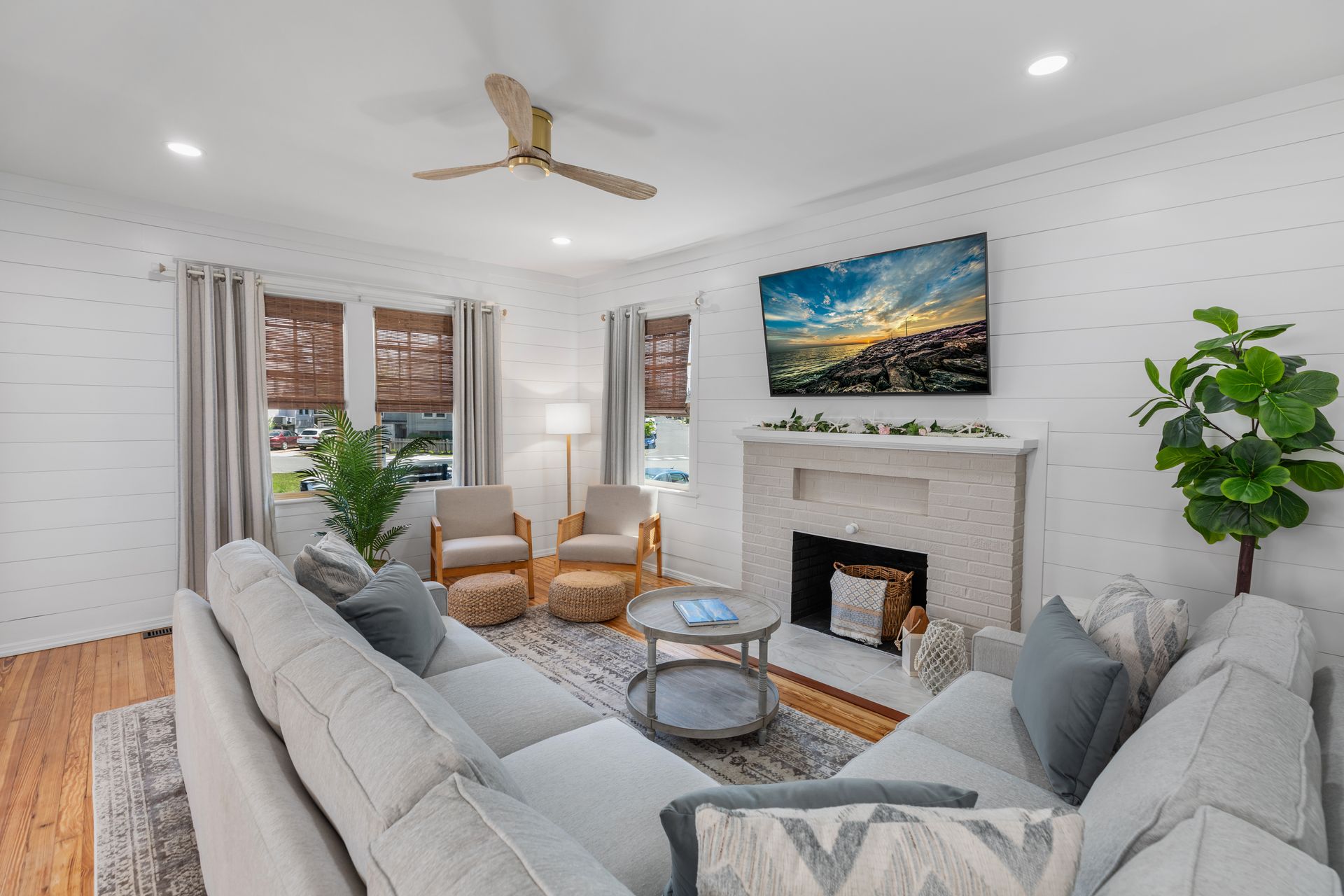 A living room with a couch , chairs , fireplace and ceiling fan.
