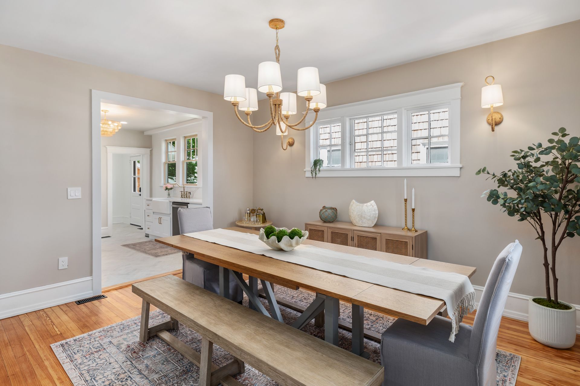 A dining room with a wooden table , bench , chairs and a chandelier.