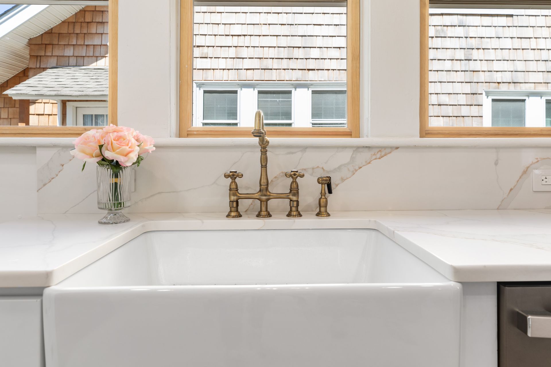 A white kitchen sink with a vase of flowers on the counter.