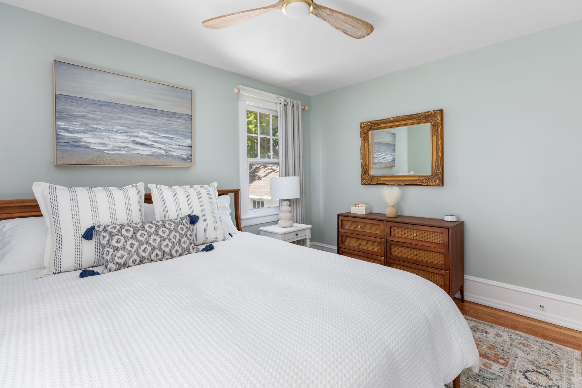 A bedroom with a bed , dresser , mirror and ceiling fan.