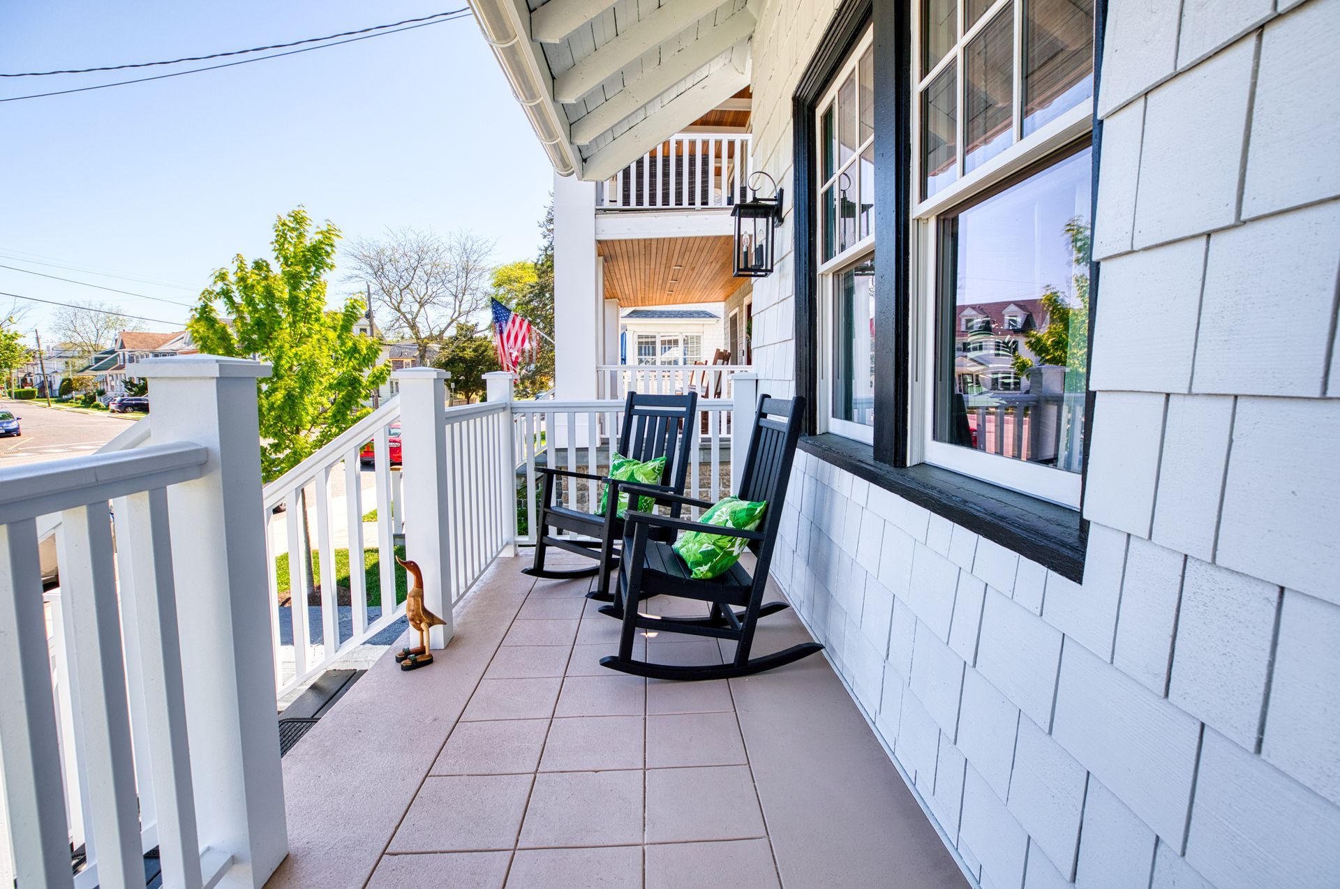 There are two rocking chairs on the porch of a house.