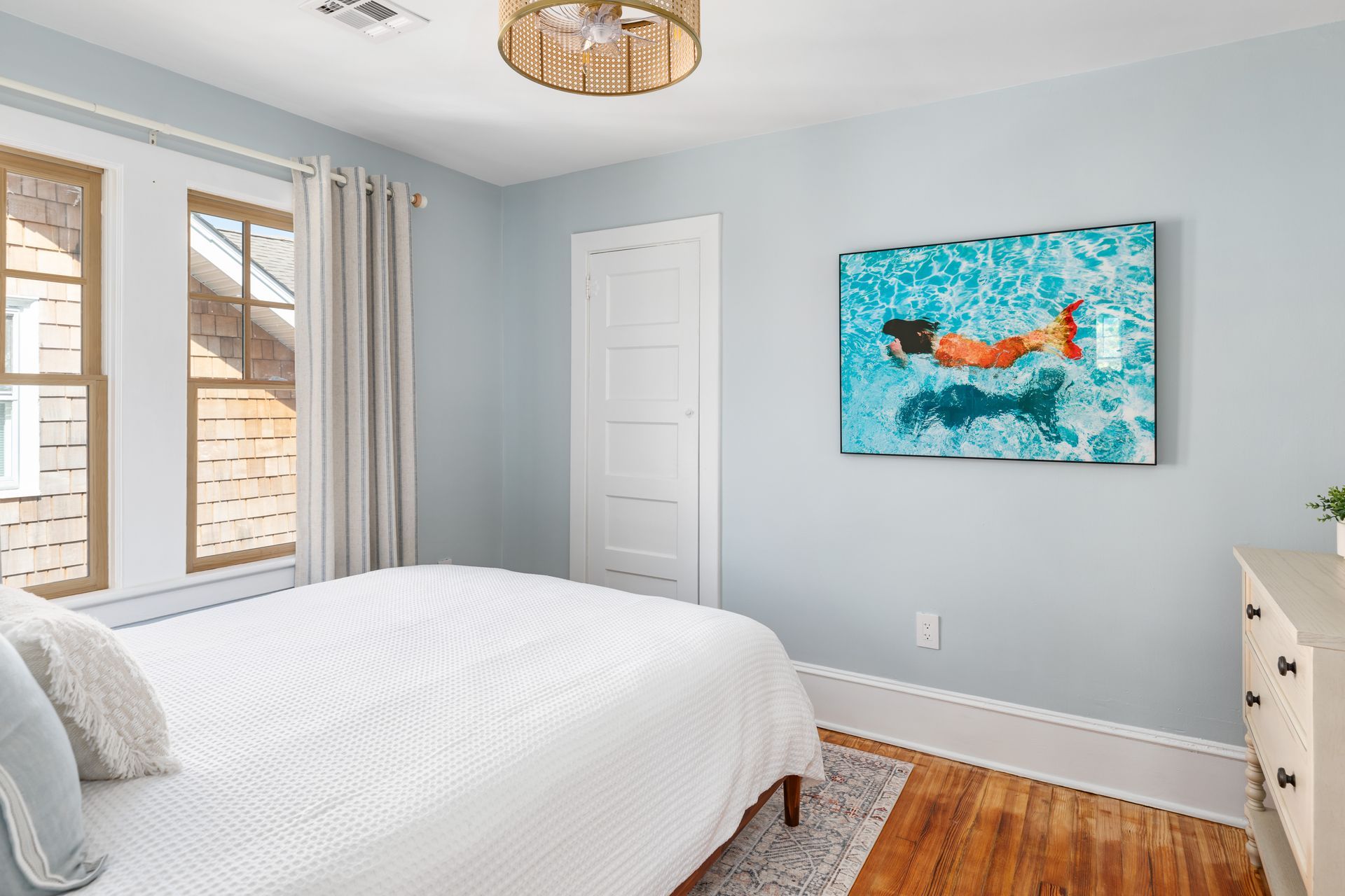 A bedroom with a bed and a painting on the wall.