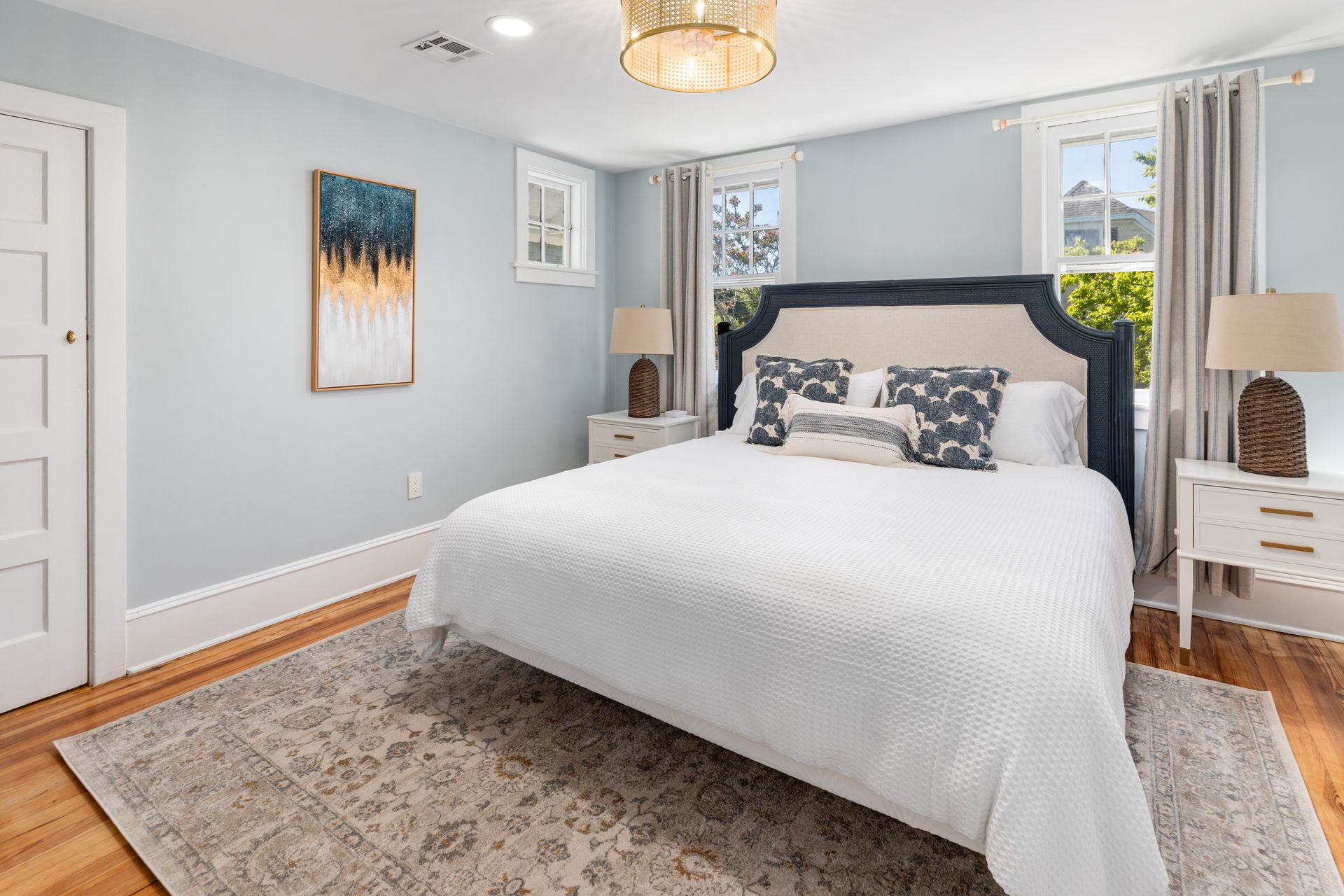 A bedroom with a king size bed , nightstands , lamps and a rug.