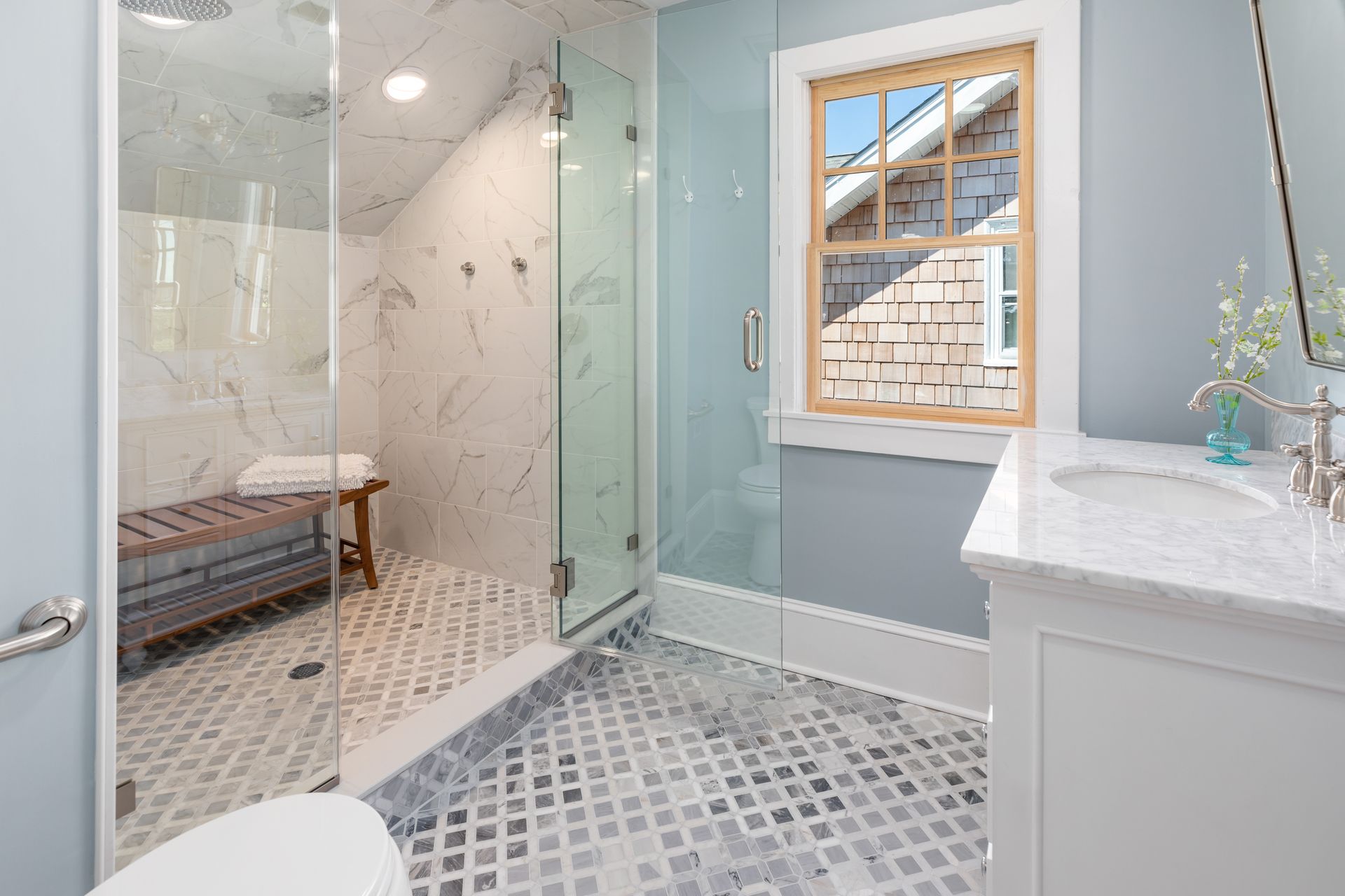 A bathroom with a walk in shower , toilet , sink and window.
