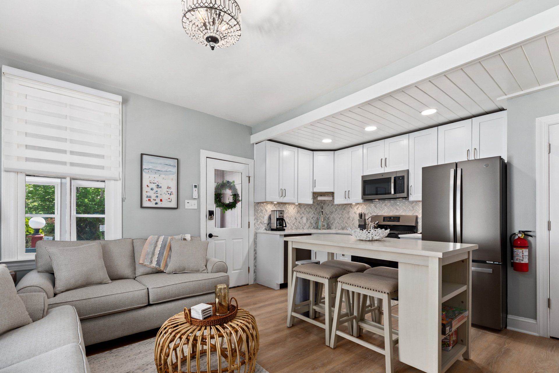 A living room and kitchen in a house with white cabinets and stainless steel appliances.