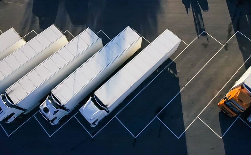 A row of semi trucks are parked in a parking lot