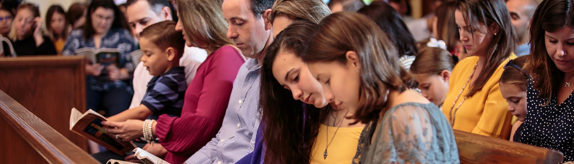 A group of people are sitting in a church reading the bible.