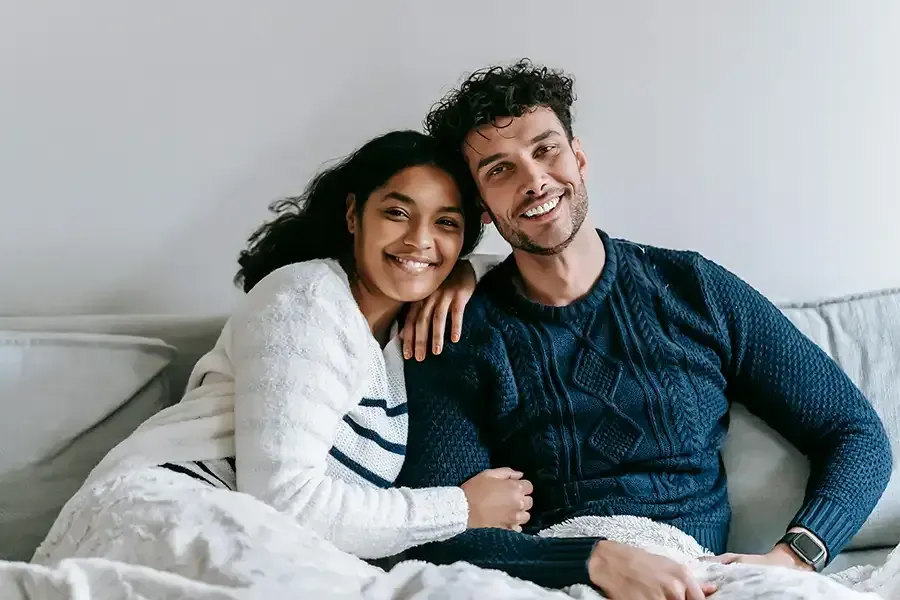 Family of four hugging in a bright room, smiling close together