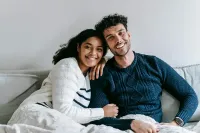Family of four hugging in a bright room, smiling close together