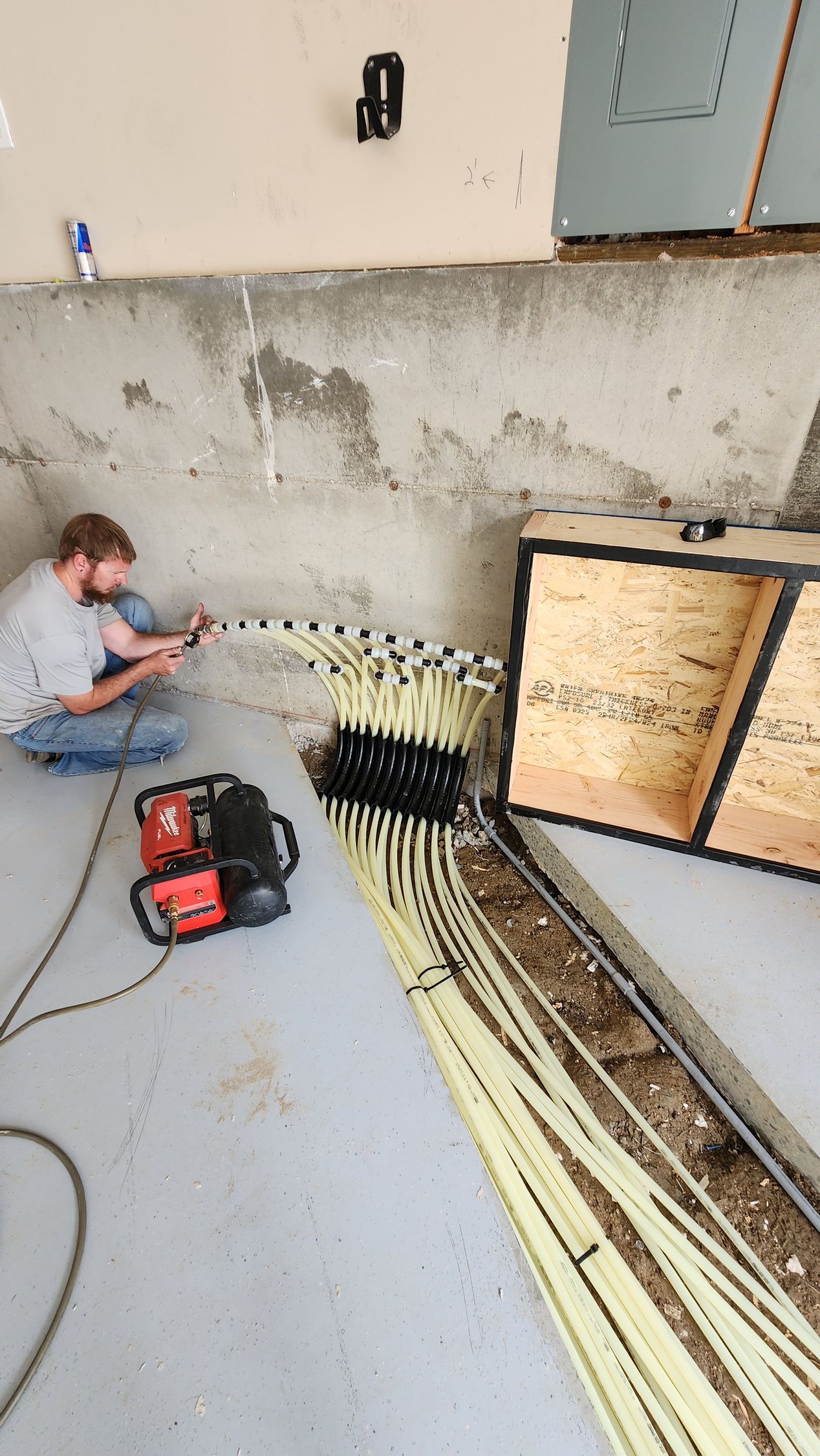 Floor heating system installation, red and white pipes laid across a room, near windows with a view.