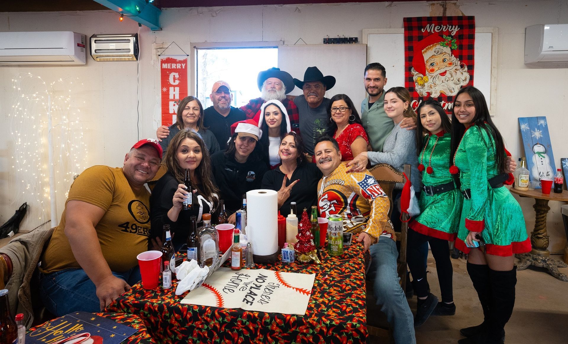 Group in festive holiday costumes posing around a decorated table with confetti and holiday decorations