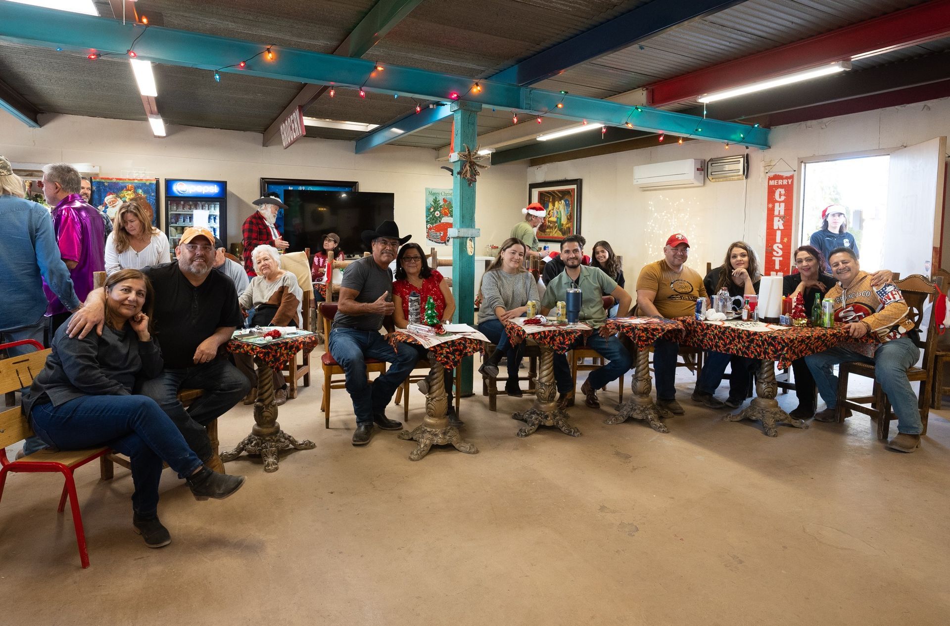 People seated around tables in a bright café, chatting and drinking together.