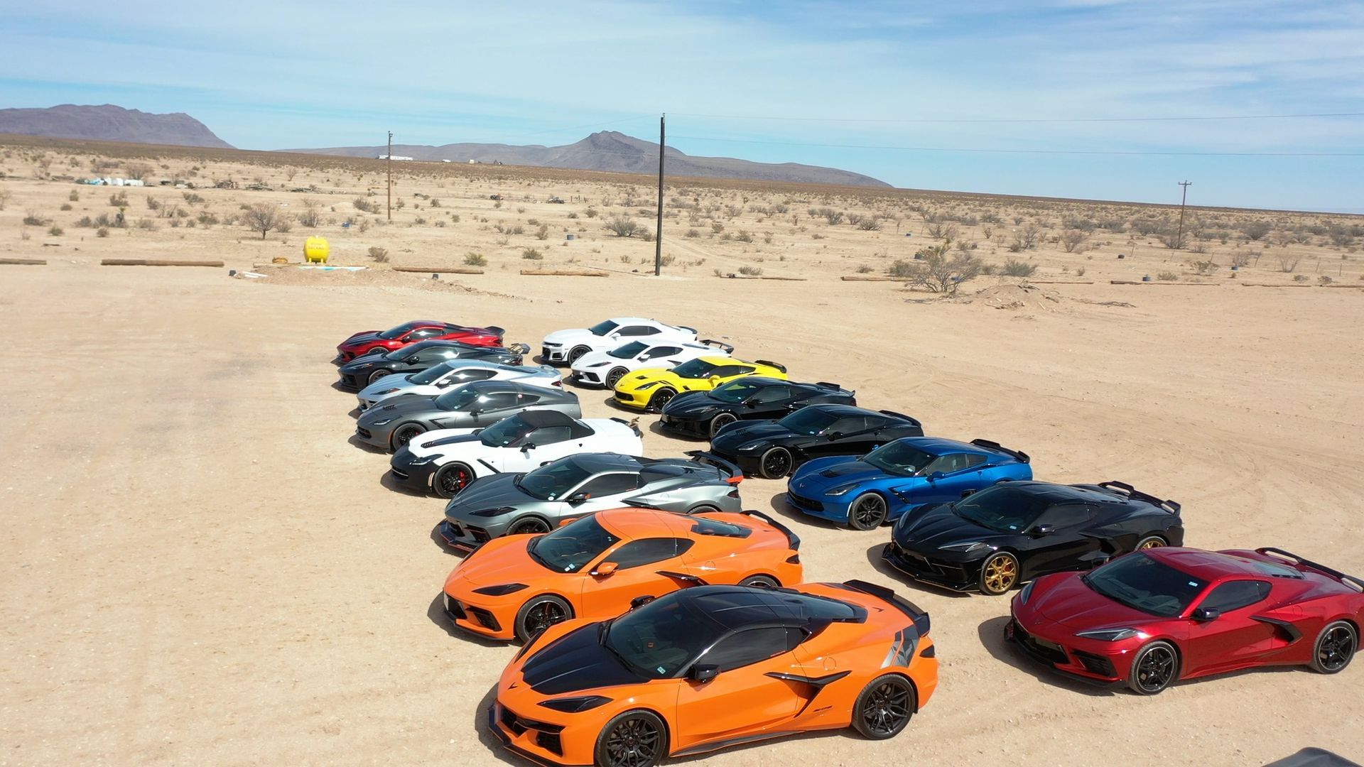 Rows of colorful sports cars parked in a desert landscape under a clear sky