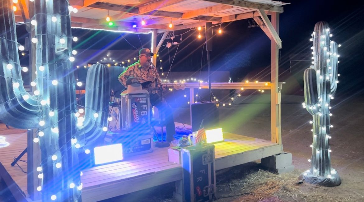 Nighttime porch decorated with glowing string lights and lit cactus-shaped sculptures.
