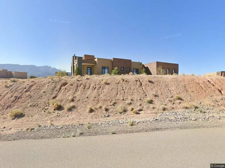 Desert hillside home with tan stucco walls under a clear blue sky