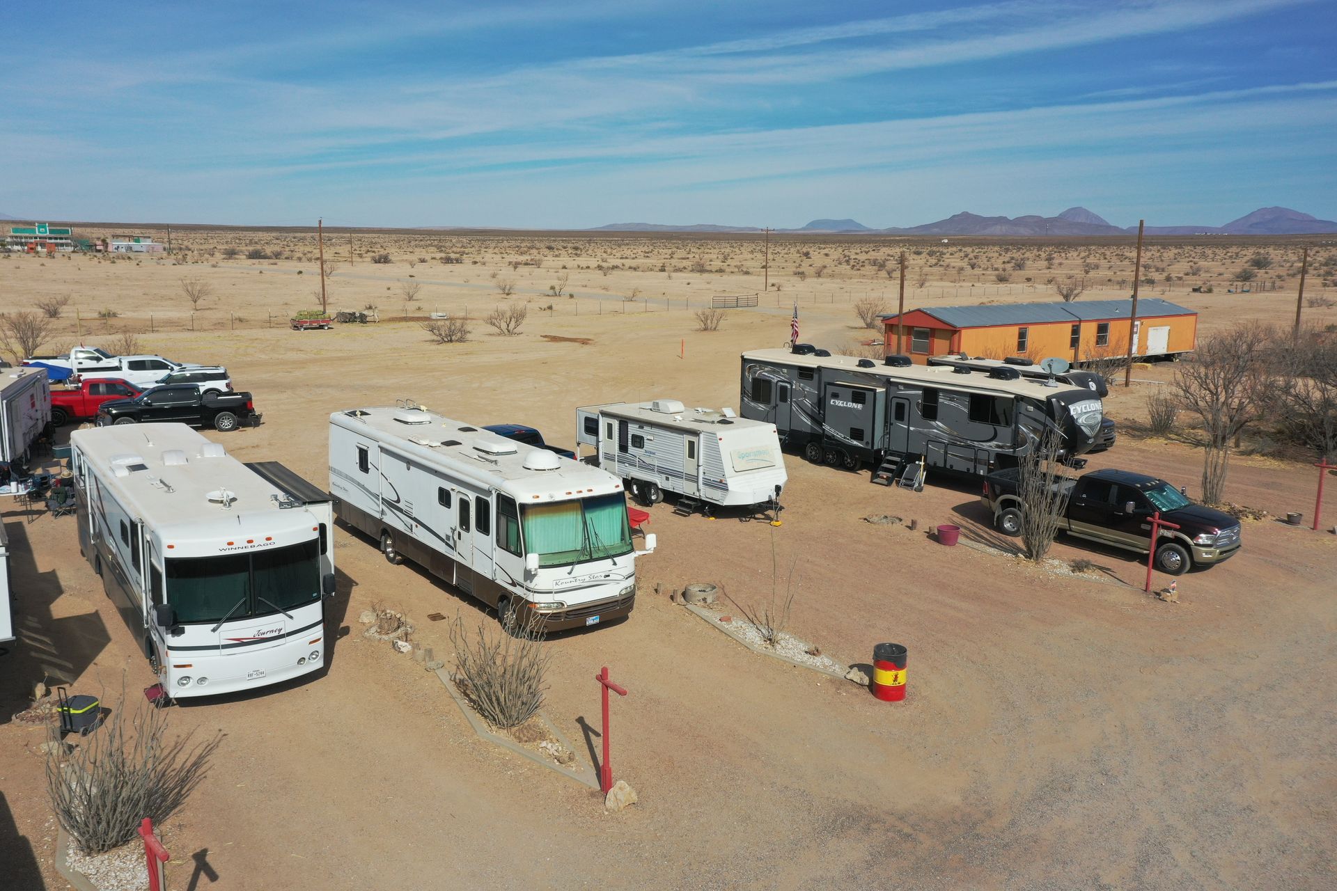 RVs and trucks parked in a desert campsite under a clear blue sky.