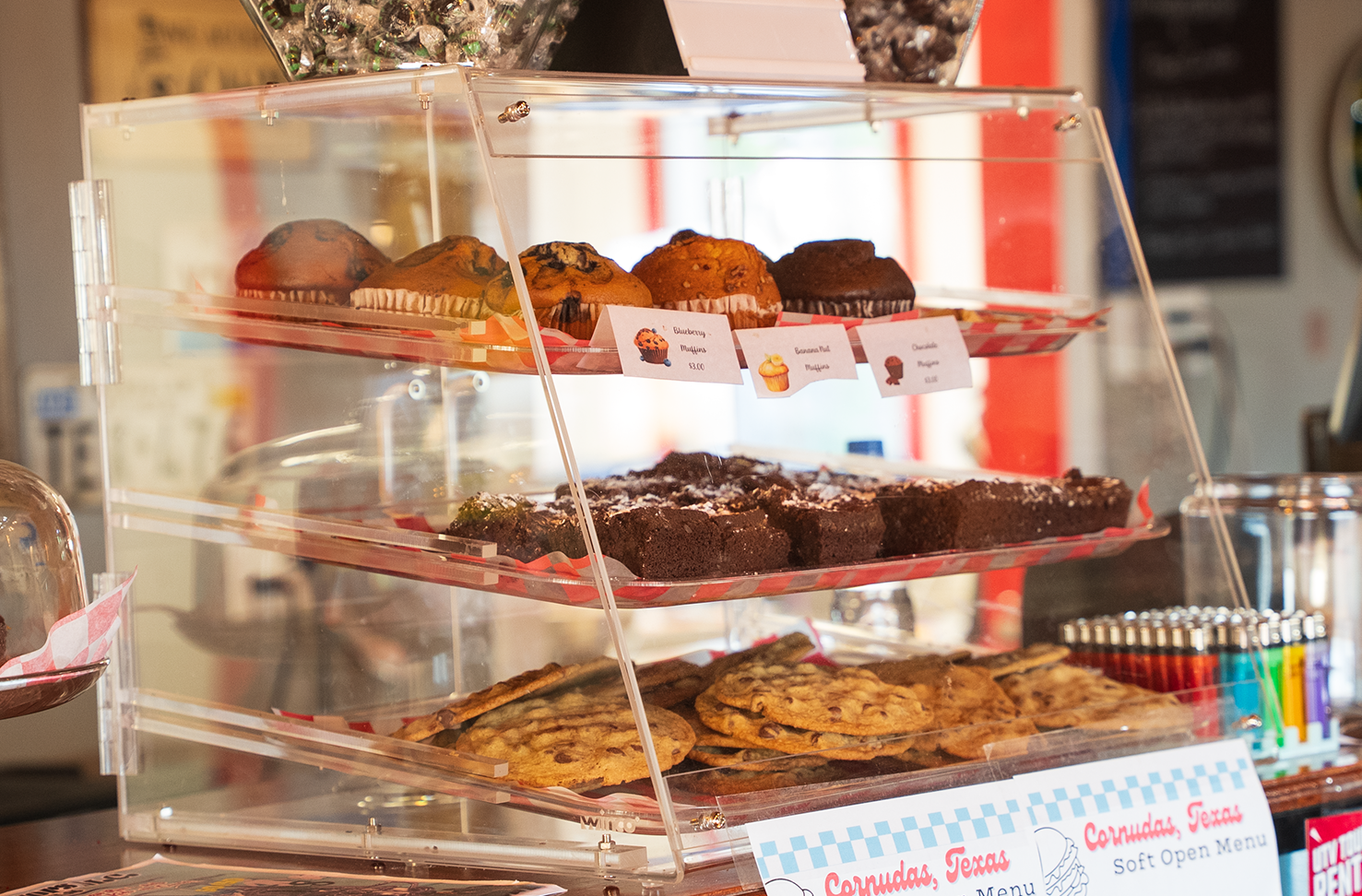 Dessert display case with assorted pastries and cakes on glass shelves, lit by warm bakery lights