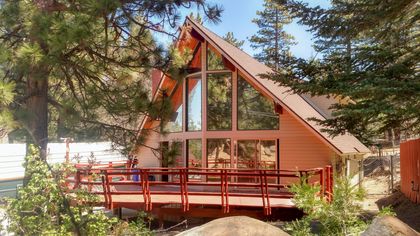 A house with a bridge in front of it surrounded by trees