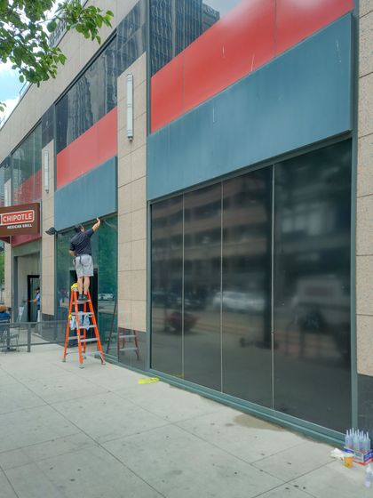 A man on a ladder is cleaning the windows of a building