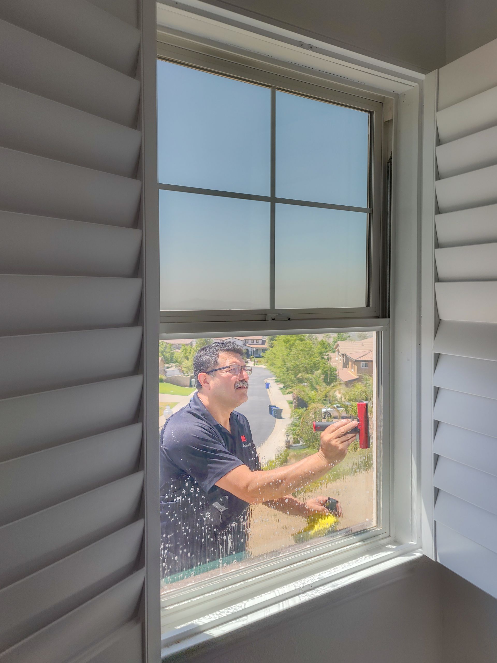A man is cleaning a window with a brush.