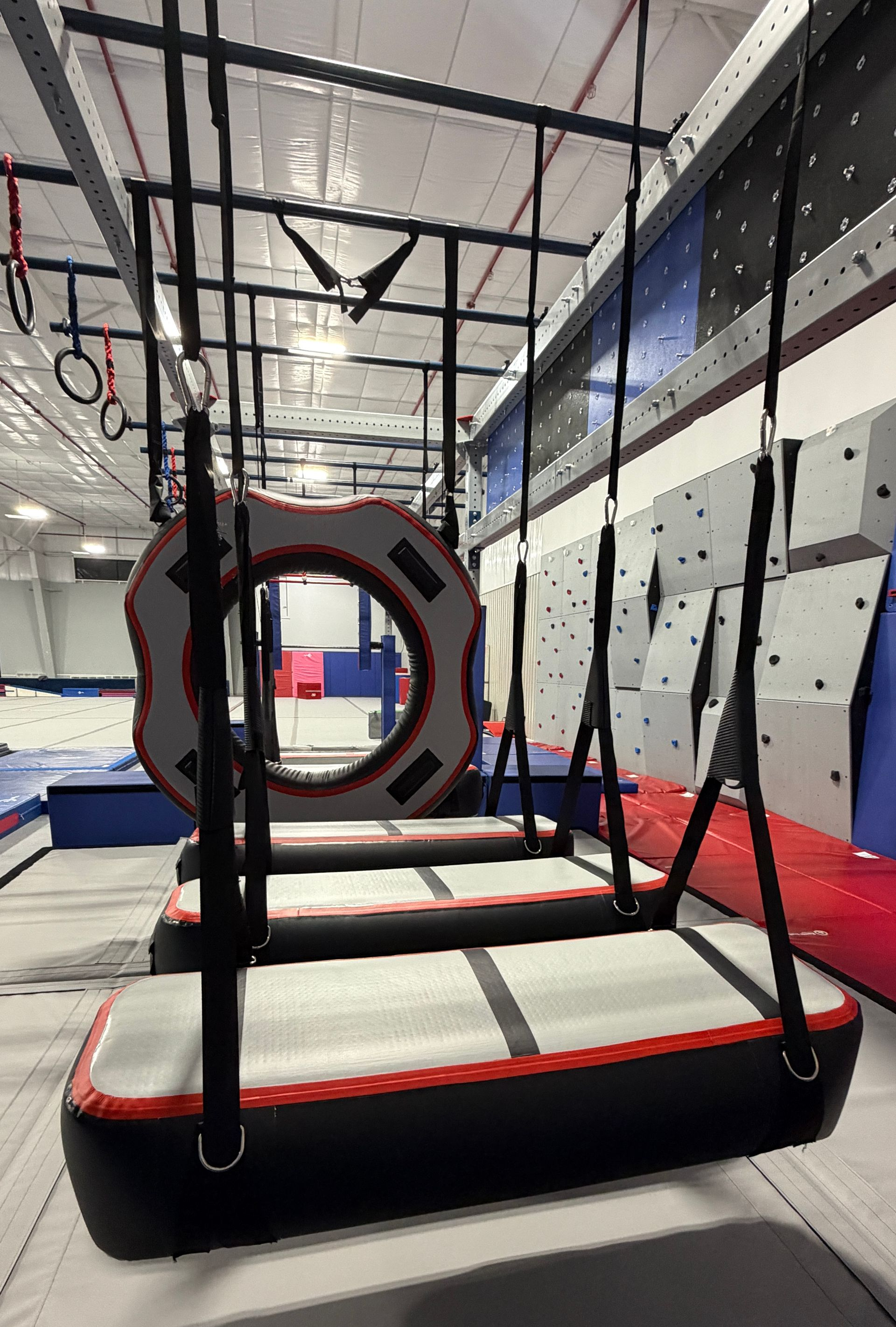 A young boy is playing with gymnastic rings in a gym.