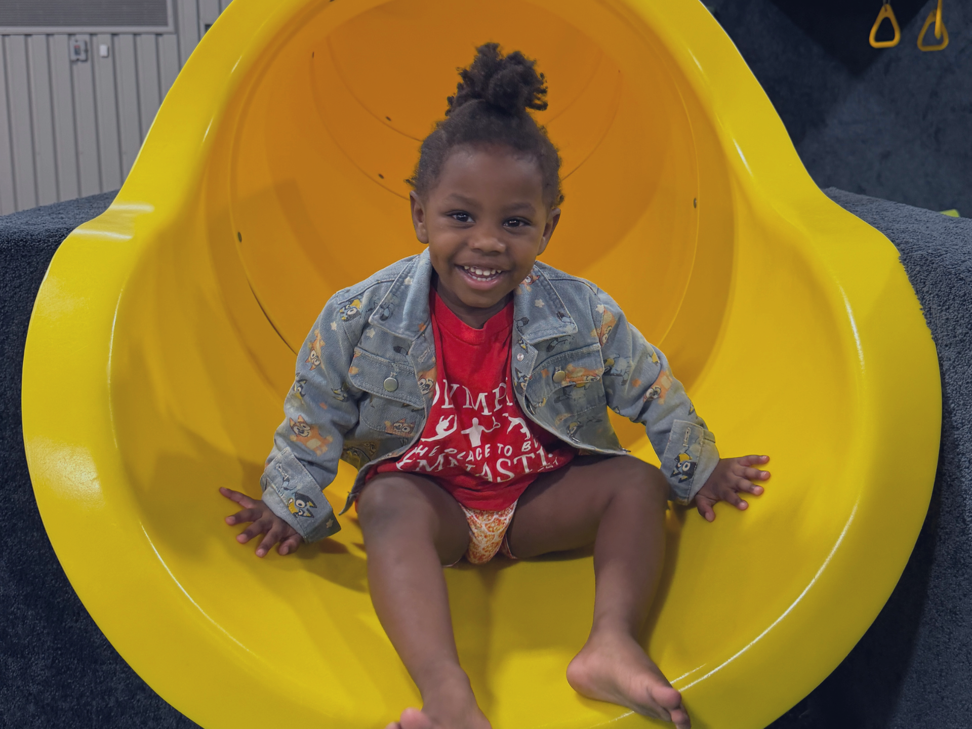 A little girl is sitting in a pile of green foam blocks.