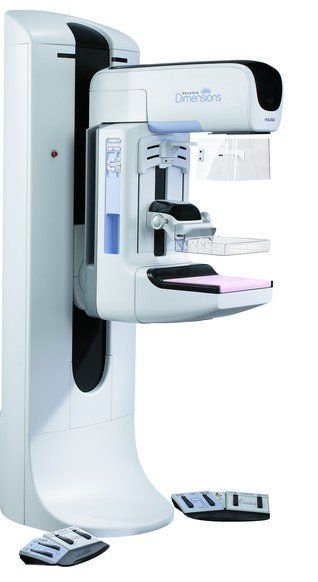 Apparecchio radiografico dentale bianco e grigio con poltrona e pedali in un ambiente clinico.