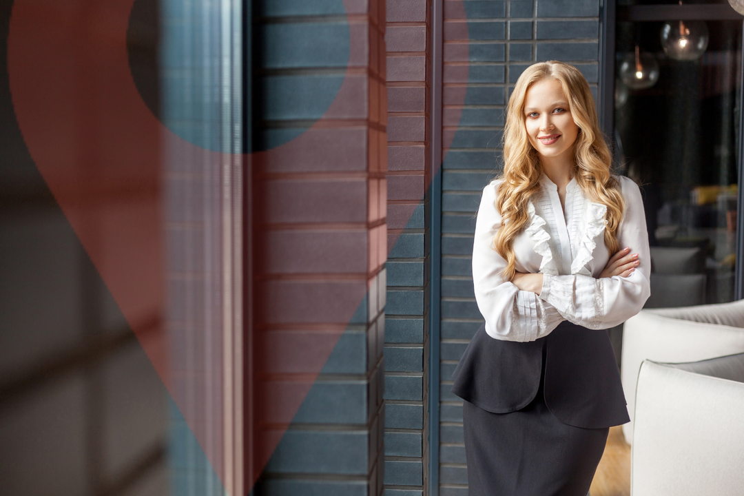 A woman is standing in front of a building with her arms crossed.
