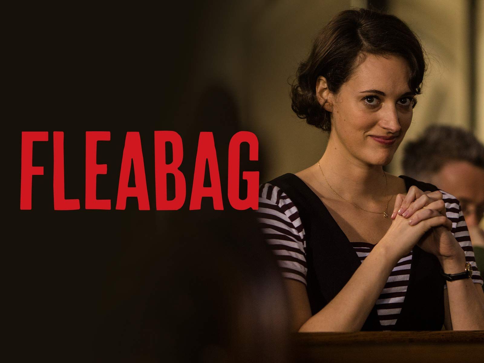 una donna è seduta a un tavolo con le mani incrociate davanti al logo fleabag