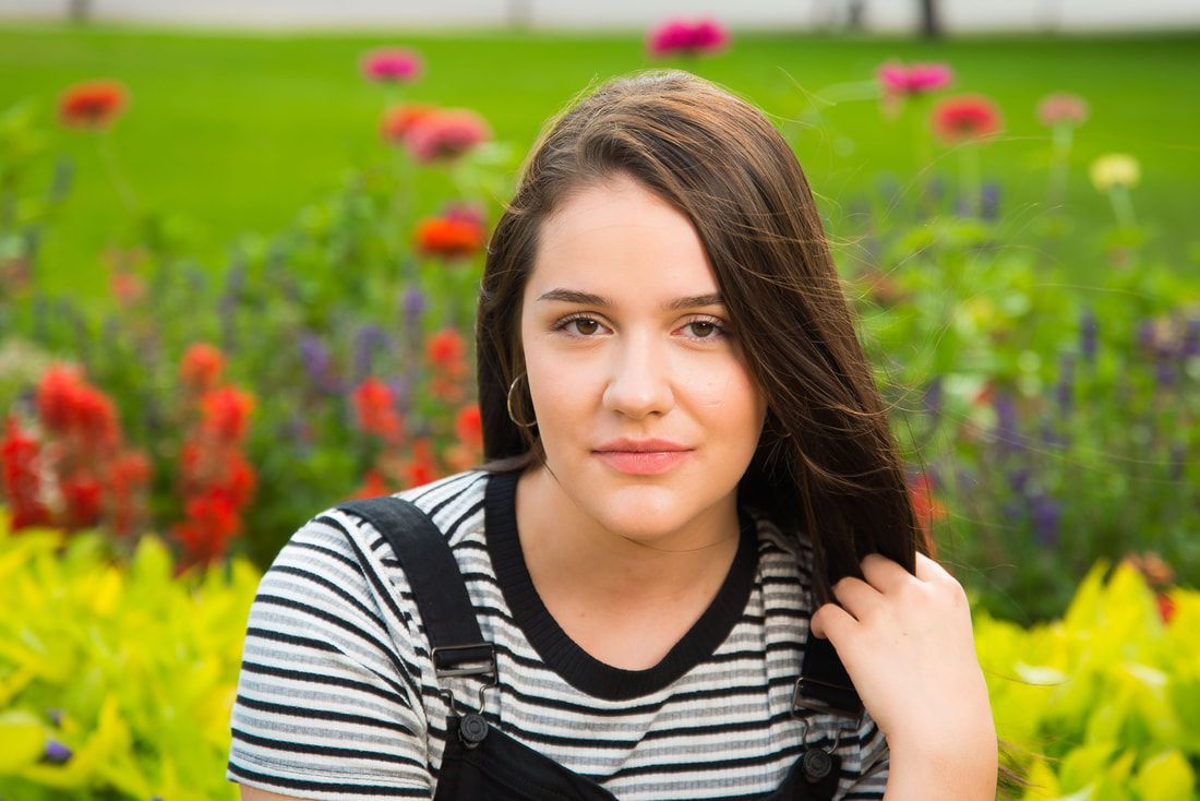 A young woman is standing in front of a field of flowers.