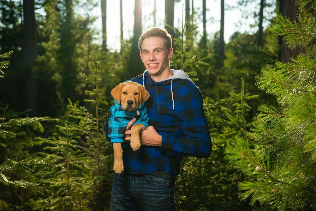 A man is holding a puppy in his arms in a forest.