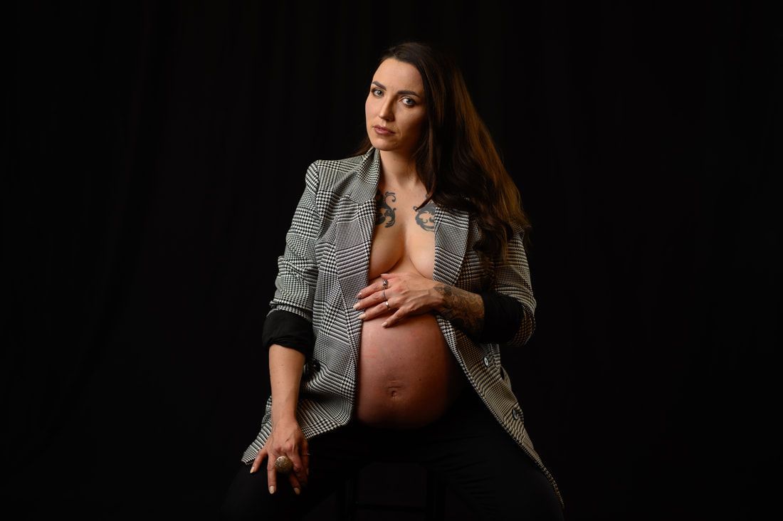 A pregnant woman is sitting down and holding her belly.