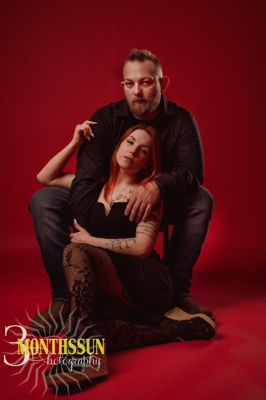A man and a woman are sitting next to each other on a red background.