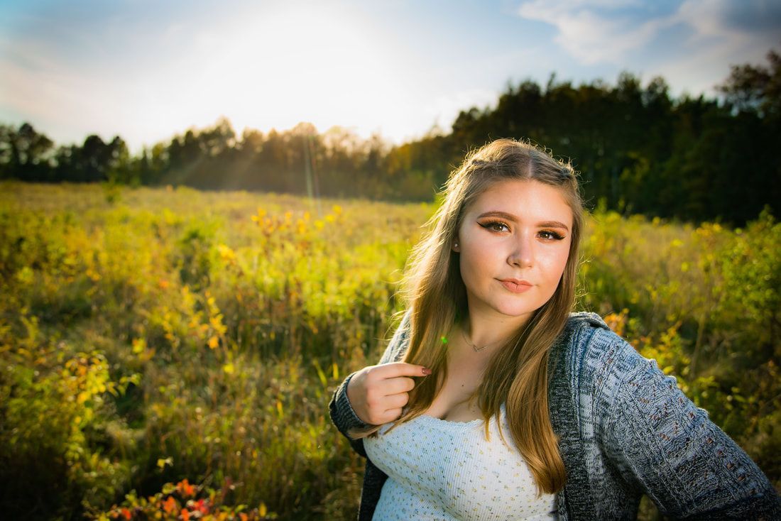 A young woman is standing in a field of tall grass.