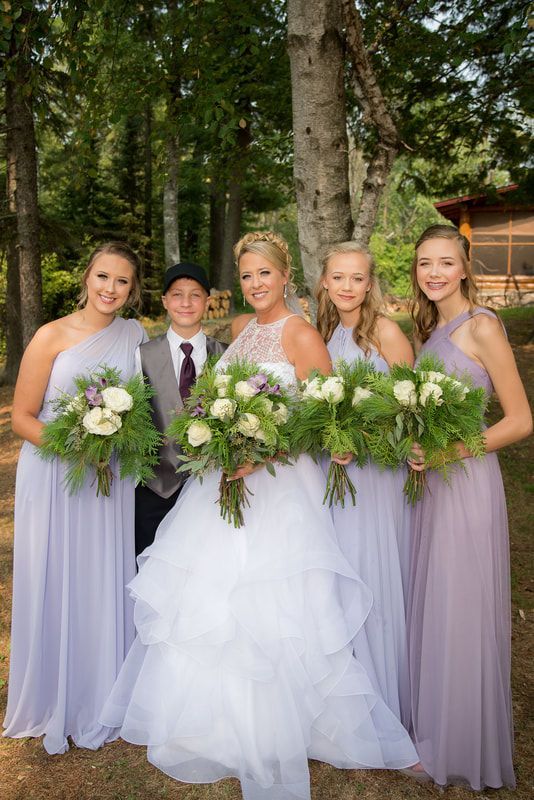 A bride and her bridesmaids are posing for a picture in the woods.