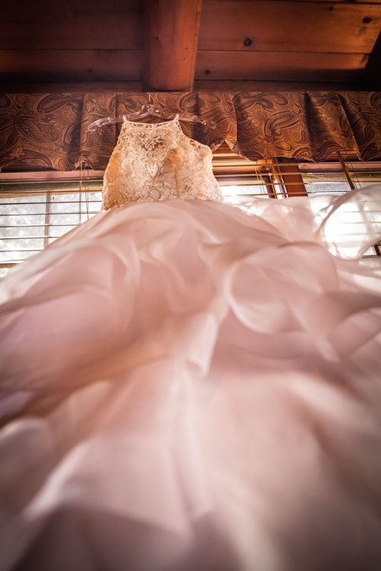 A wedding dress is hanging from the ceiling in a room.