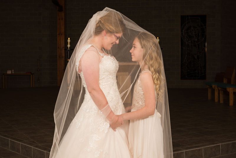 A bride and a flower girl are standing next to each other in a church.