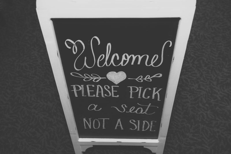 A sign that says welcomes please pick a seat not a side